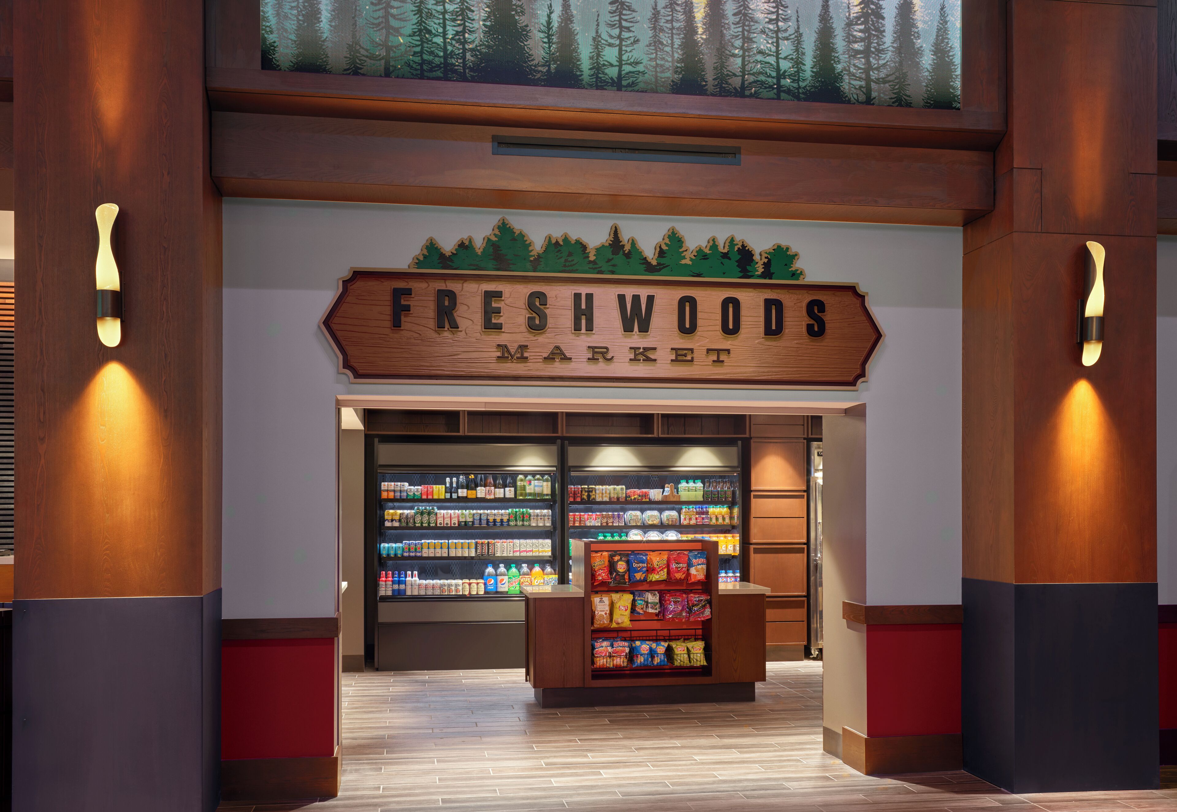 The entrance to Freshwoods Market with a wooden sign, shelves stocked with products, and a display of snacks.