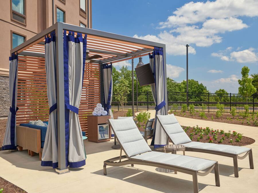 A covered outdoor seating area with lounge chairs and a wooden pergola structure.