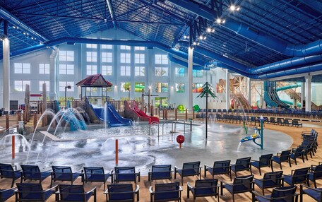 An indoor water park with multiple slides, a water fountain, and seating areas.
