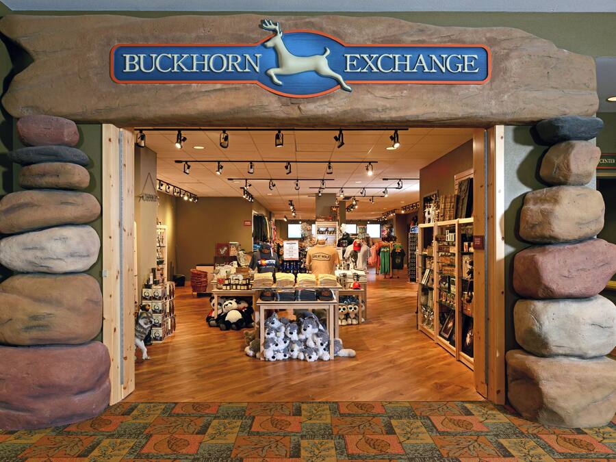 The interior of Buckhorn Exchange, featuring a rustic stone archway, wooden flooring, and various merchandise displays.
