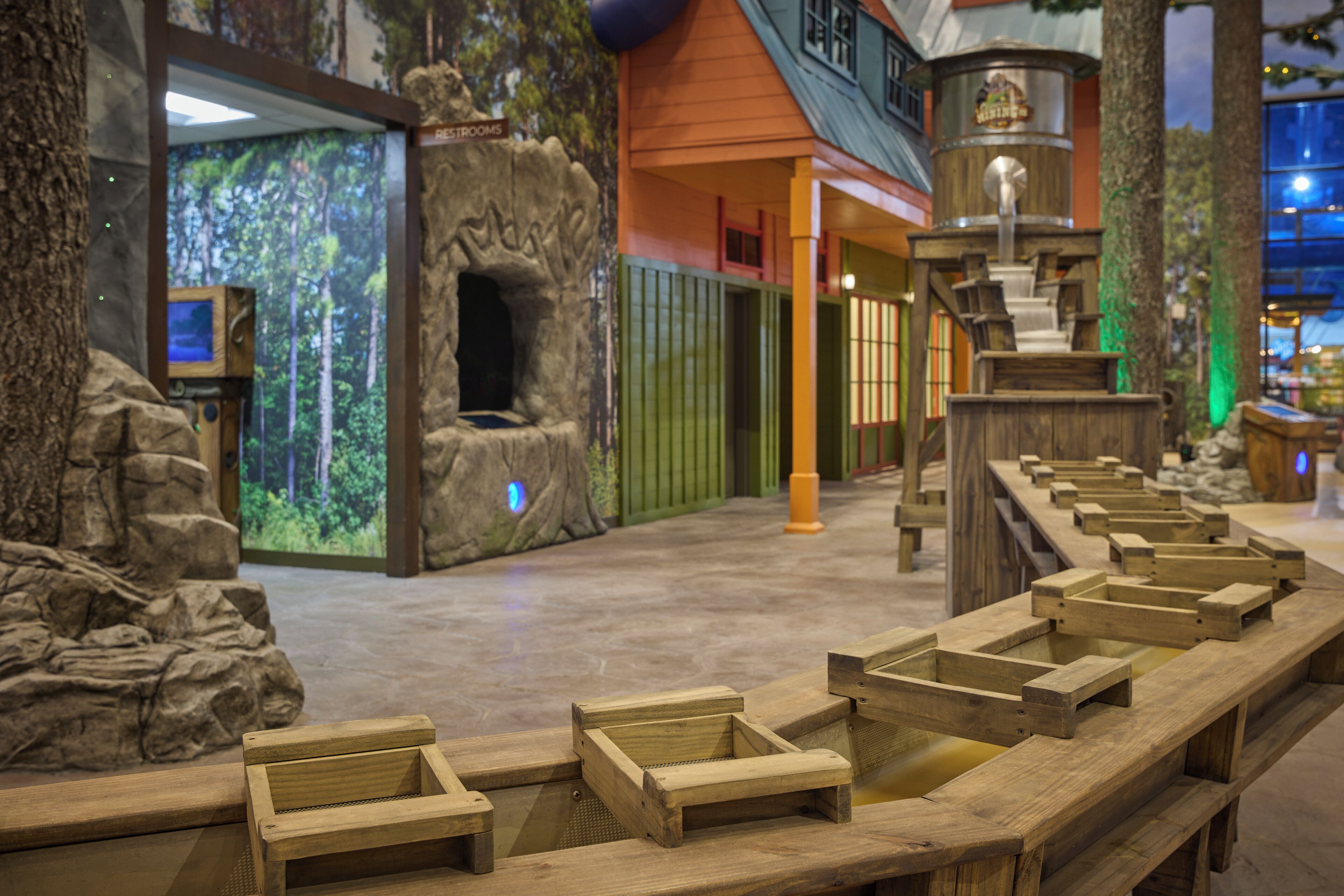 A wooden bench area with a stone wall and a projection screen displaying a forest scene.