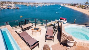 A poolside area with lounge chairs, a hot tub, and a view of a marina with boats. - 7 Bed Waterfront W/Rooftop pool & hot tub stunning 360-degree bay & beach view (Newport Beach)