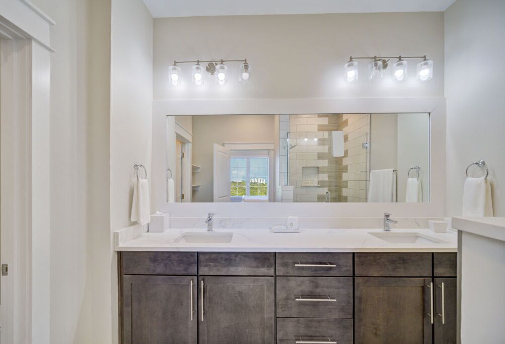 A modern bathroom with a large mirror, two sinks, and dark wood cabinets.