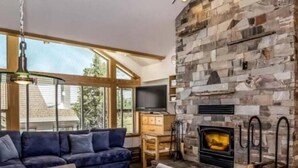 A cozy living room with a stone fireplace, a large window, and a comfortable sofa. - 4 Bed + Loft, Gorgeous Kirkwood Condo (Kirkwood)