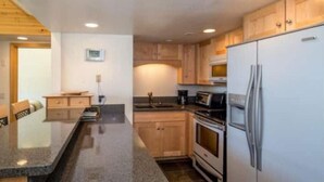 A kitchen with granite countertops, wooden cabinets, a refrigerator, an oven, and a microwave. - 4 Bed + Loft, Gorgeous Kirkwood Condo (Kirkwood)