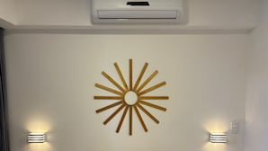 Ett modernt hotellrum med en sänggavel i trä, en solformad väggdekoration och sänglampor.