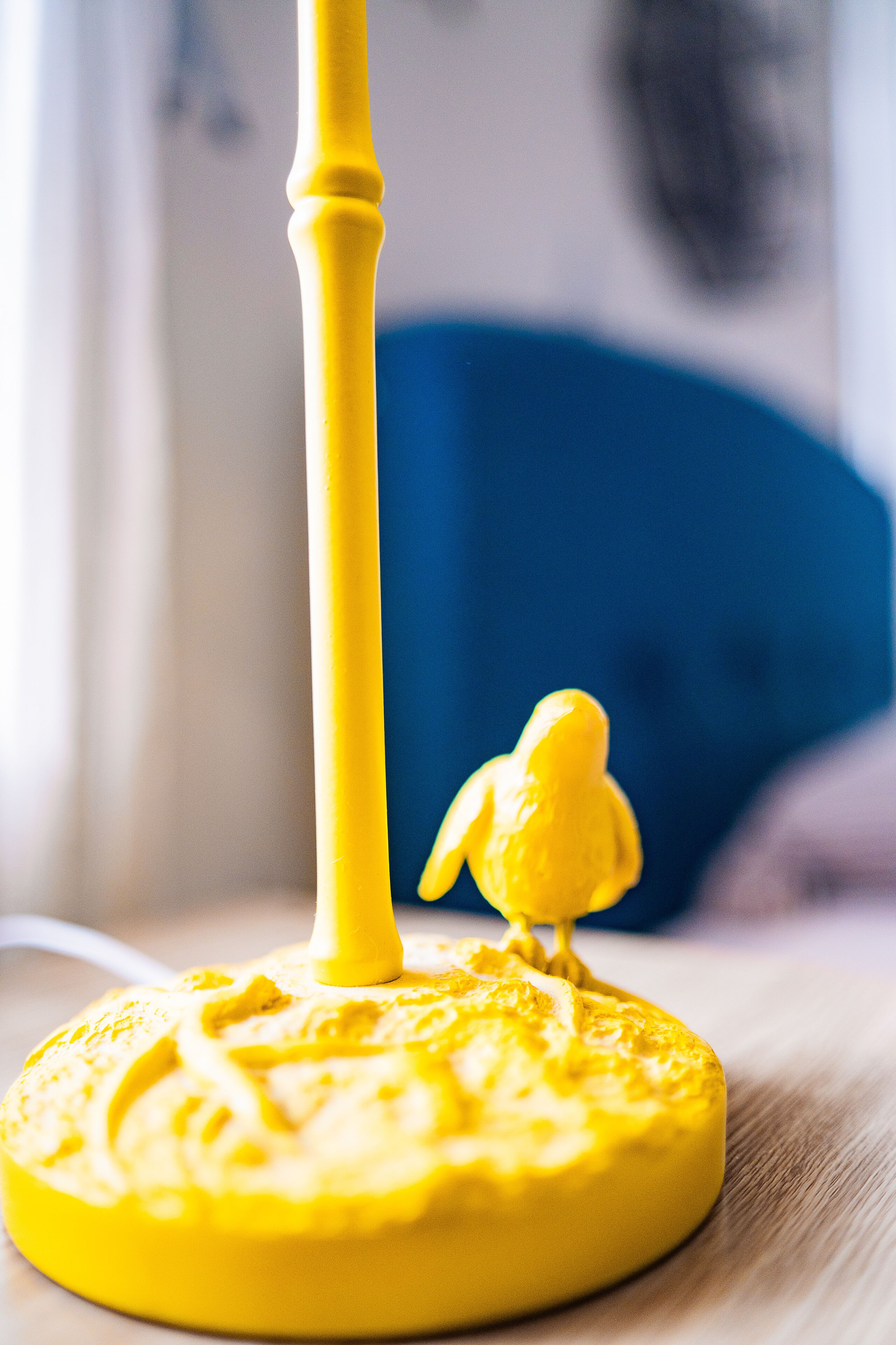 Un objet jaune sur lequel est posée une figurine d’oiseau, le tout placé sur une surface plane.