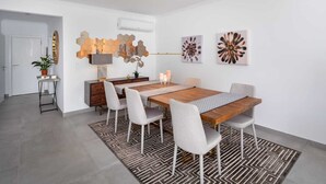Uma sala de jantar moderna com uma mesa de madeira, seis cadeiras, um tapete estampado e obras de arte nas paredes.