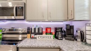 Una cocina con electrodomésticos de acero inoxidable, una estación de café y un cartel que dice 'COFFEE'.