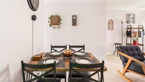 Un comedor con una mesa de madera y cuatro sillas, un reloj en la pared y un cartel de bienvenida.