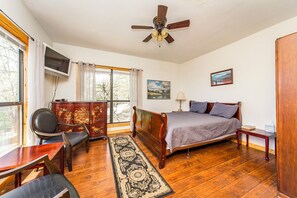 Relax in this serene bedroom with a comfortable bed, nightstand, and bedside table, offering a view of the outdoors.