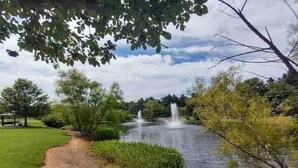 Un parc avec un étang, un kiosque et une fontaine.