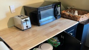 Een kleine keuken met een broodrooster, magnetron en een koelkast.