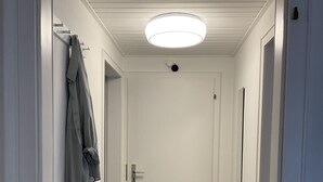 A hallway with a wooden floor, white walls, a white door, and a hanging garment. - Wohnung in Idyllischem Örtchen (Meschede)