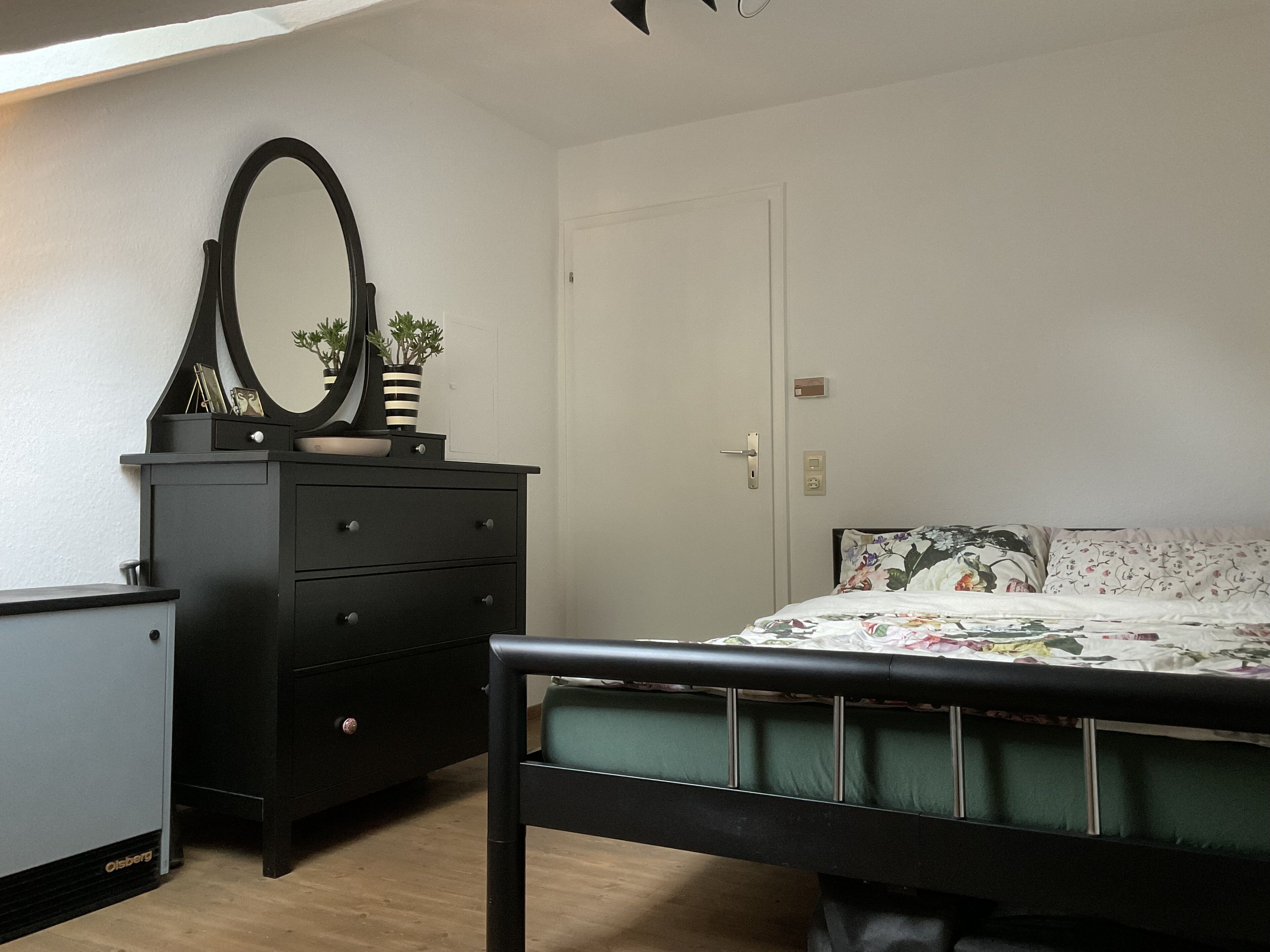 Een slaapkamer met een bed, een dressoir en een spiegel.