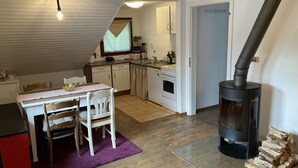 A compact kitchen with a dining area, a stove, and a wood-burning stove. - Wohnung in Idyllischem Örtchen (Meschede)