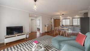 Una sala de estar moderna con televisor, sofá y comedor.