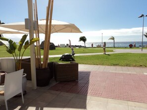 Un patio con mobiliario exterior, vistas al mar y un sendero que lleva a la playa.