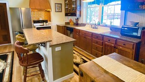 Una cocina con una isla central, armarios de madera, horno empotrado y ventana con vistas.