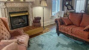 Una sala de estar con chimenea, sofá, sillón y lámpara.