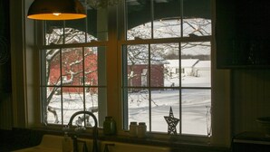 Una cocina con vista a un paisaje nevado por la ventana, un fregadero y una lámpara colgante.