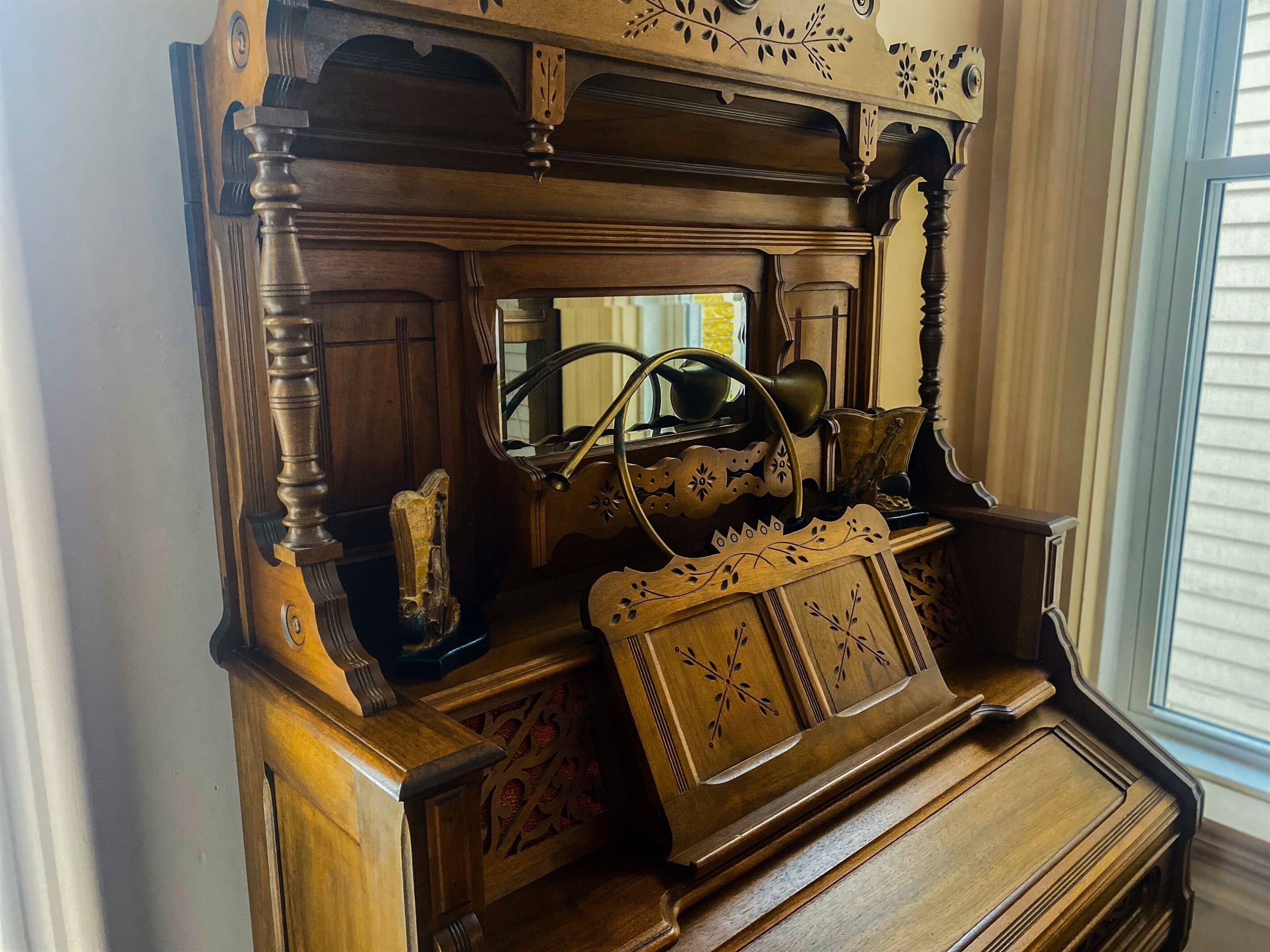 Un piano en bois orné de sculptures complexes, avec un miroir placé au-dessus.