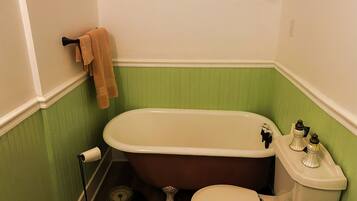 A bathroom with a freestanding bathtub, toilet, and a scale on the floor.