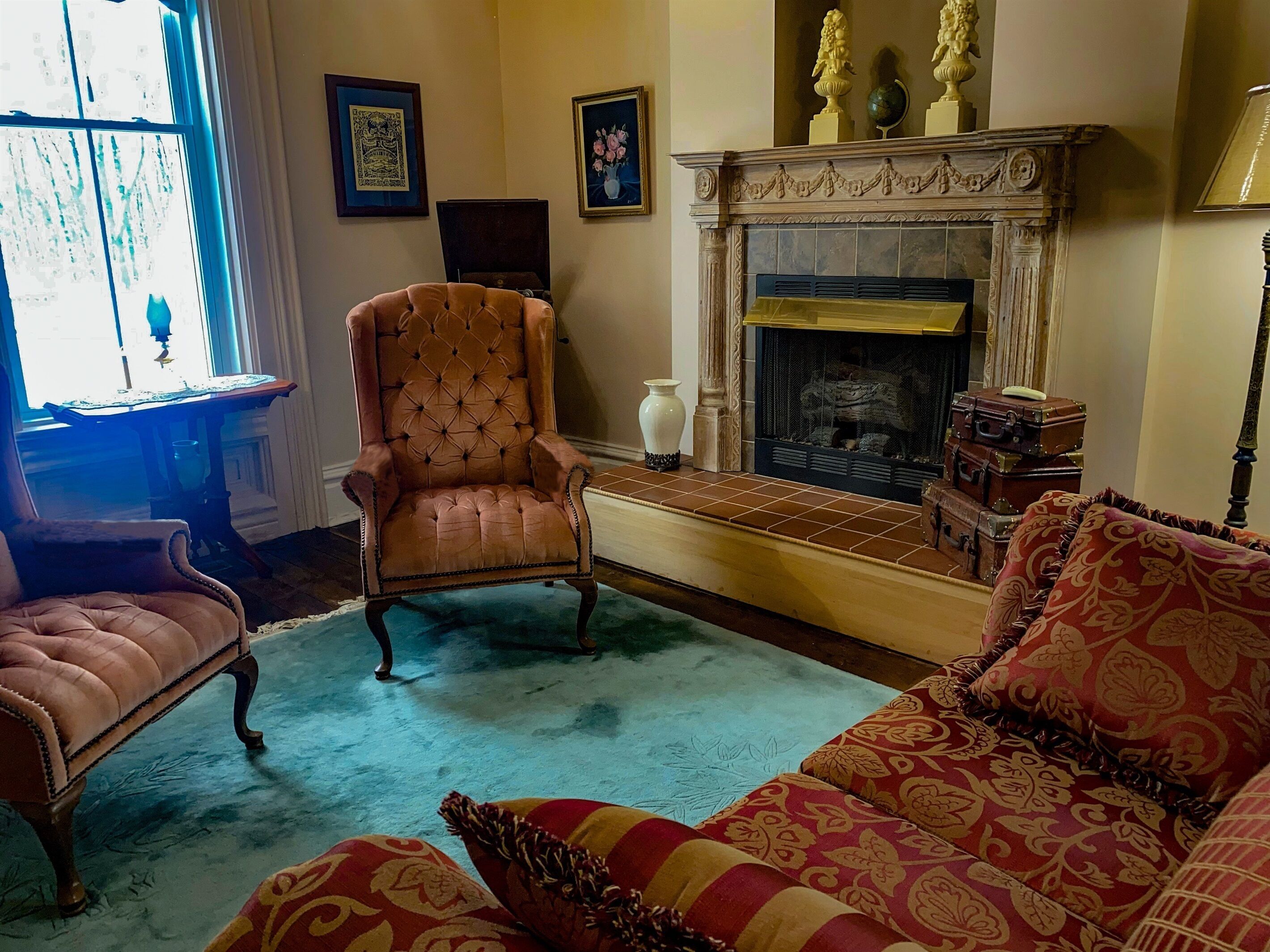 A room with a fireplace, a chair, a sofa, and a table with a vase.