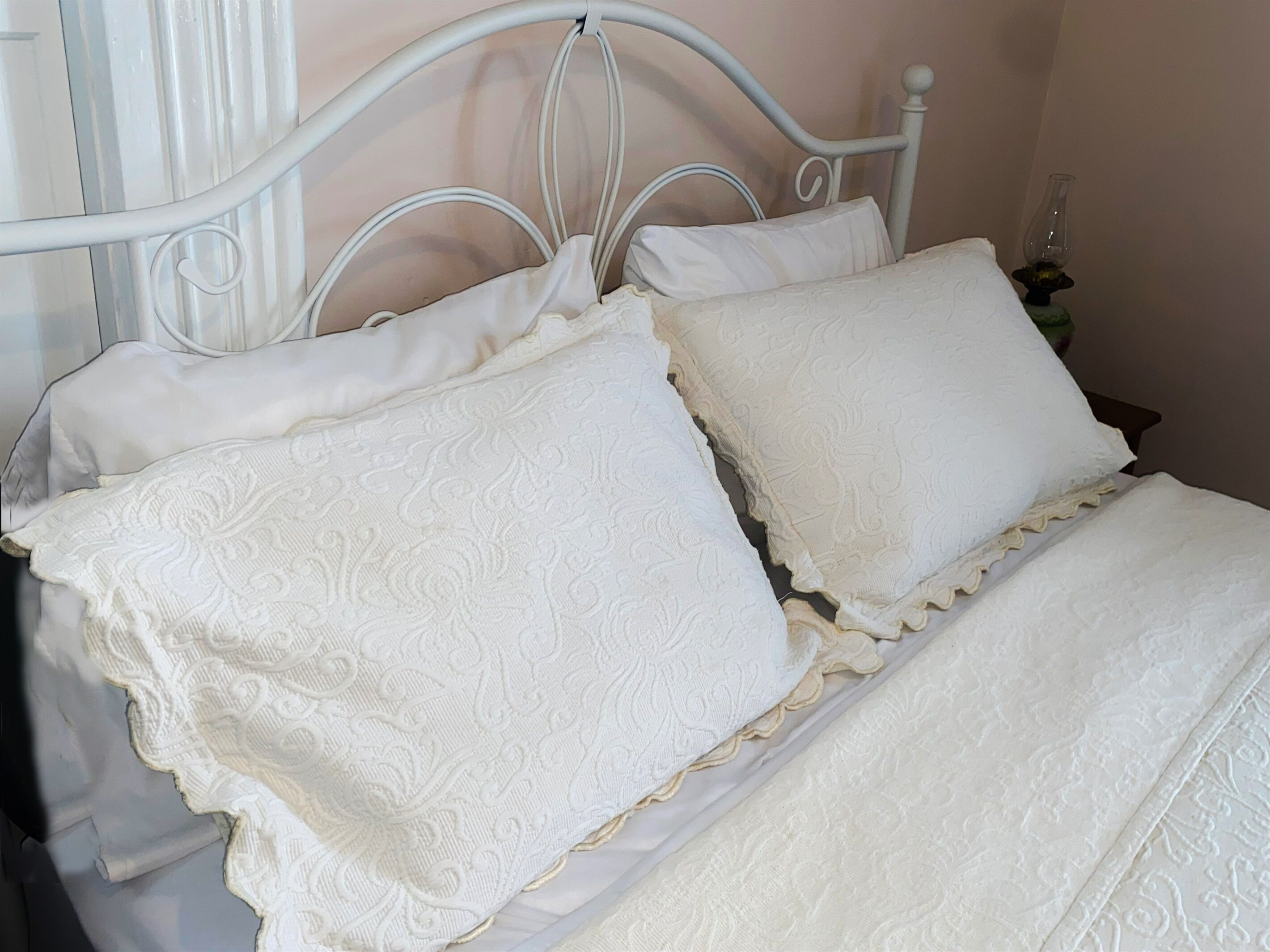 A bed with white bedding and a metal headboard.