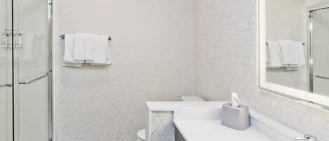 A modern bathroom with a glass shower enclosure, a white sink with a mirror, and a toilet with a towel rack.