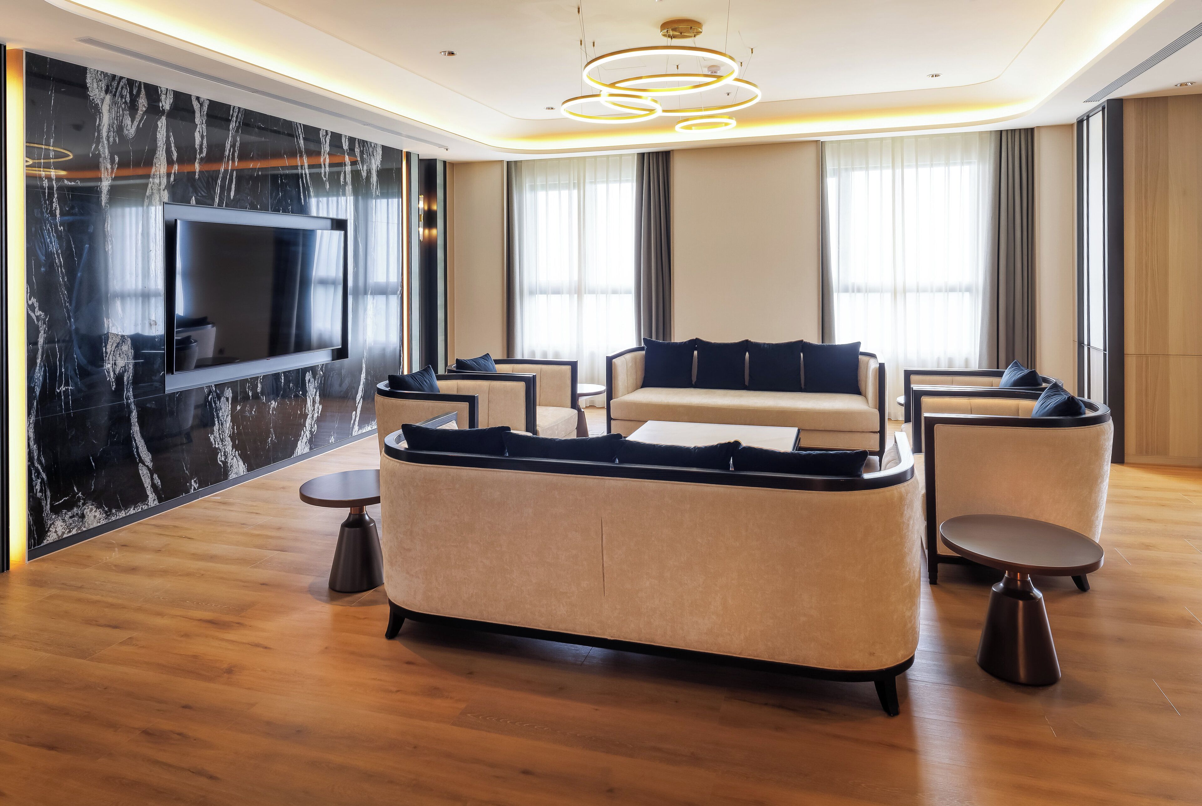 Un salon moderne doté d’un grand téléviseur à écran plat, de sièges confortables et d’un plancher en bois.