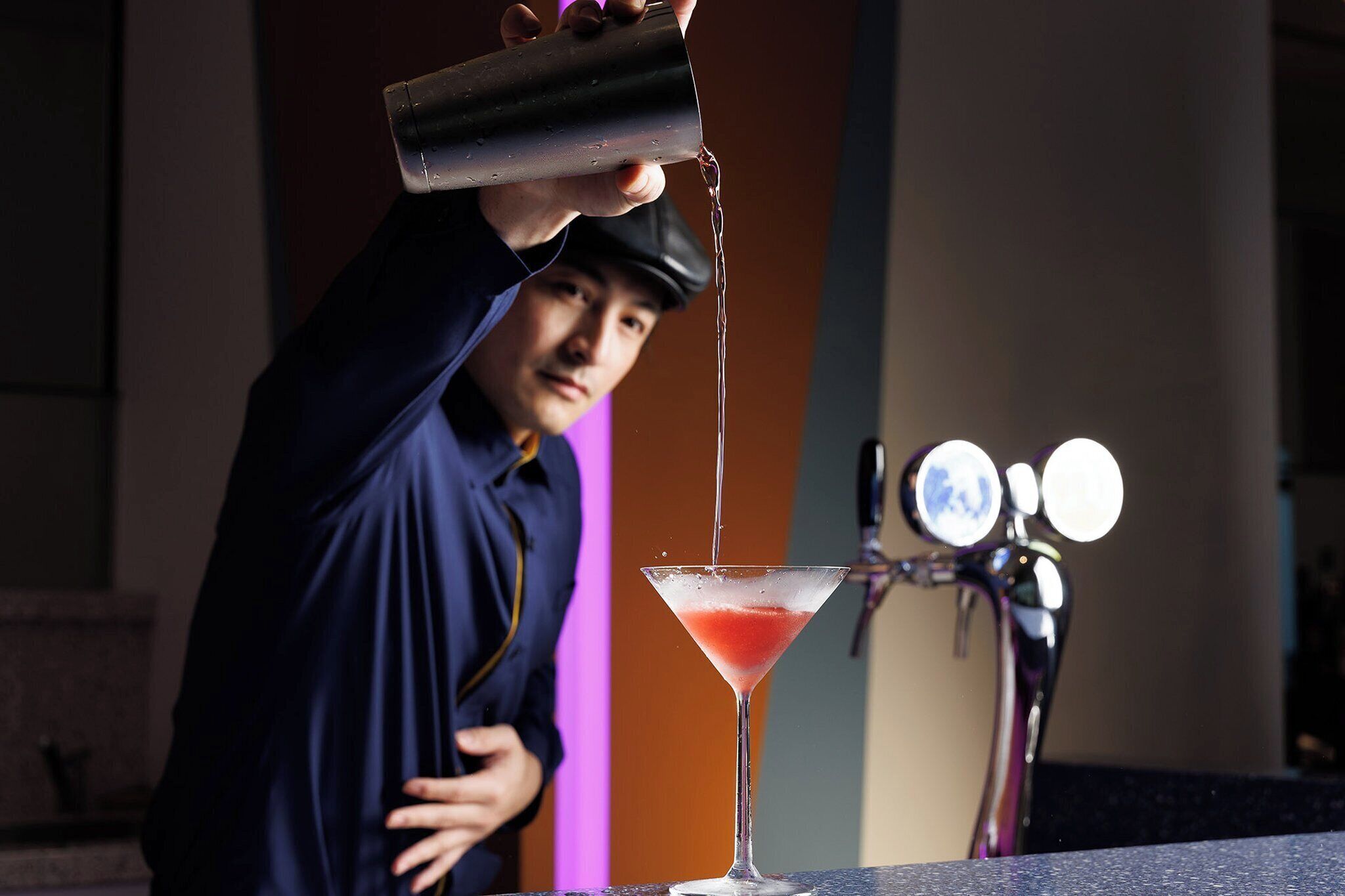 Un barman sirviendo una bebida en una copa de martini.