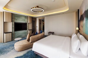 A modern hotel room with a large bed, a sofa, a TV, and a small table. - voco Chiayi by IHG (Chiayi City)