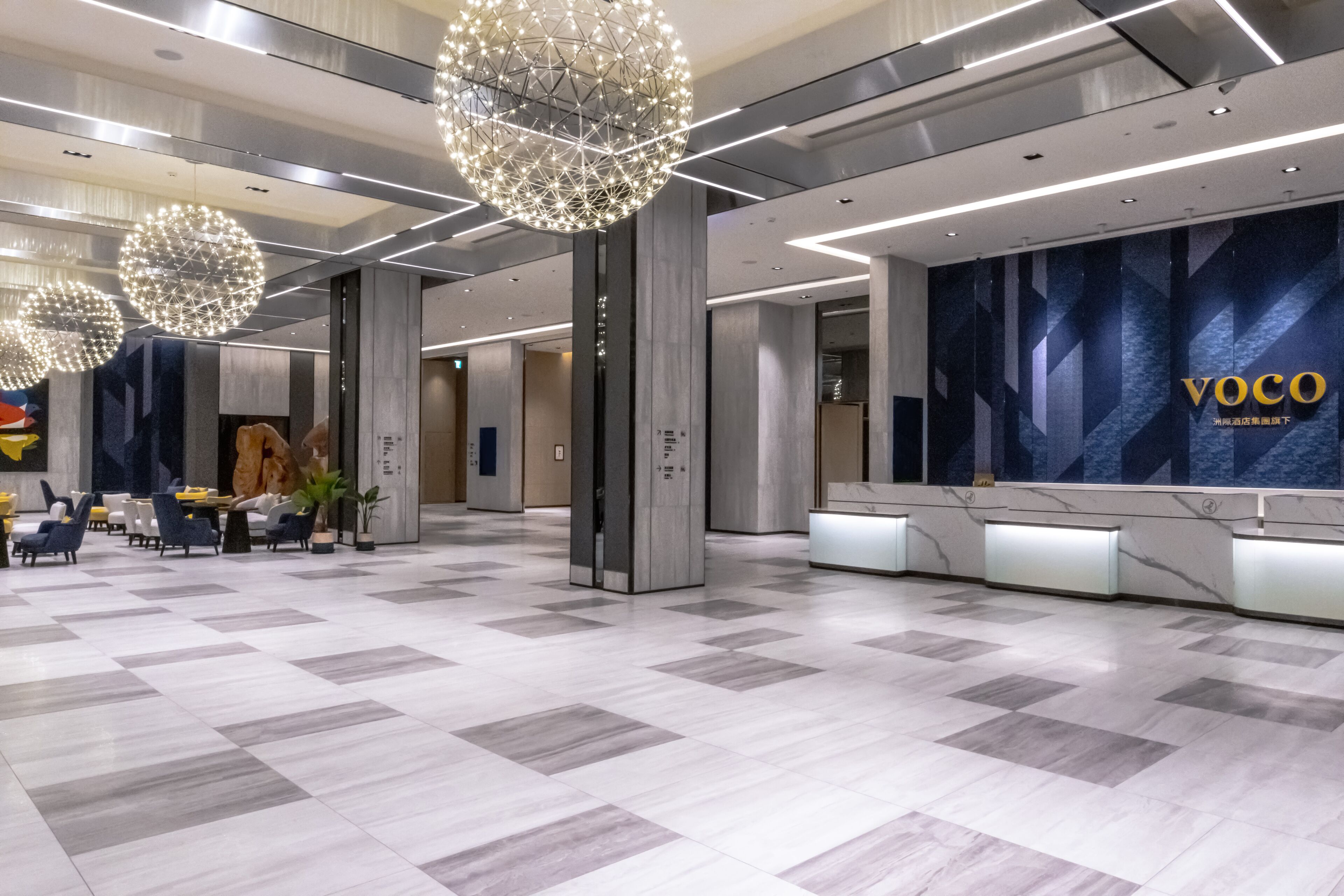 A modern lobby with a reception desk, seating area, and decorative lighting.