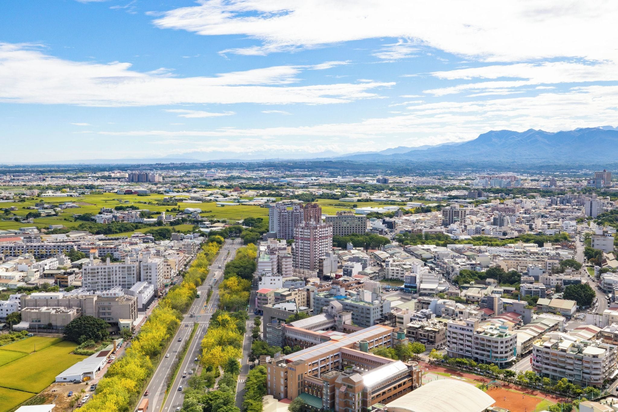Un paisaje urbano con una combinación de edificios altos y bajos, una avenida amplia y zonas verdes.