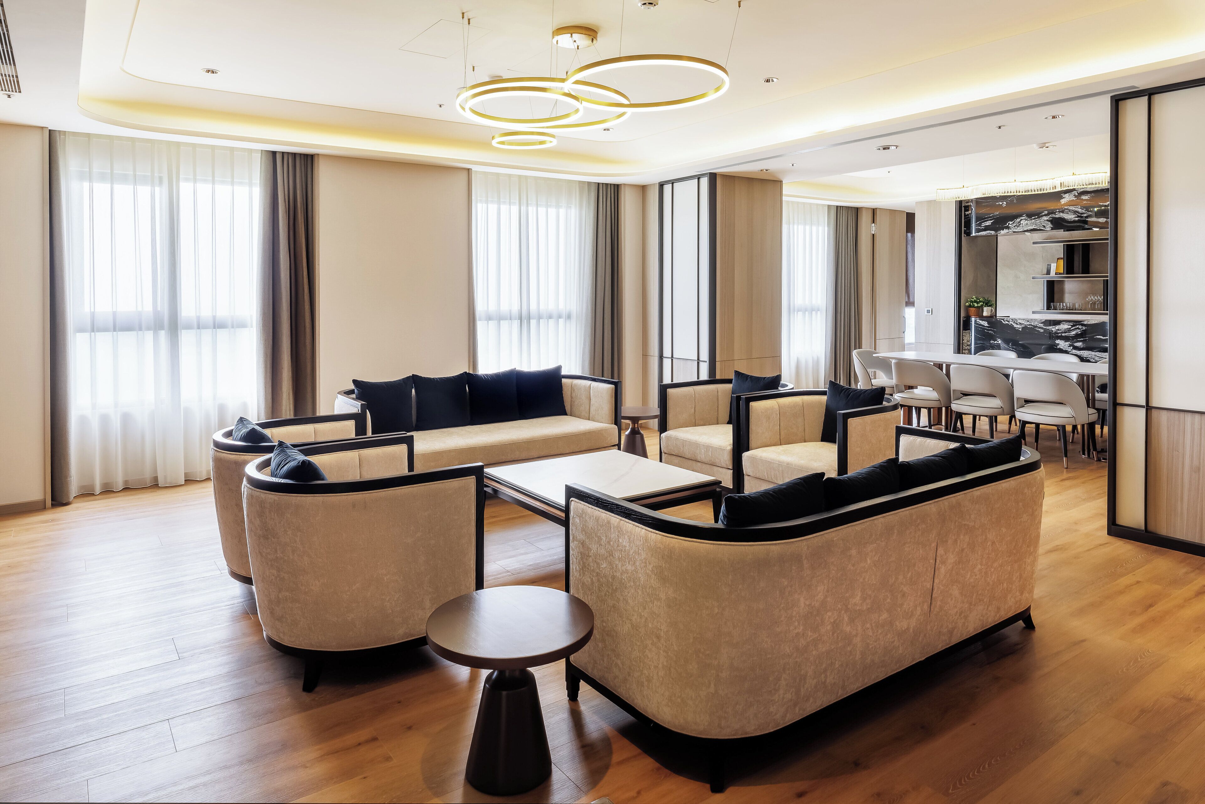 A modern living room with a sofa set, a coffee table, and a dining area with a white table and chairs.