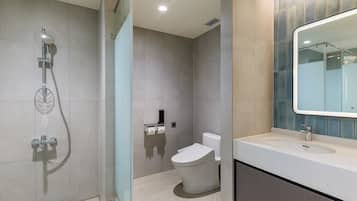 A modern bathroom with a glass-enclosed shower, a toilet, and a sink with a mirror.