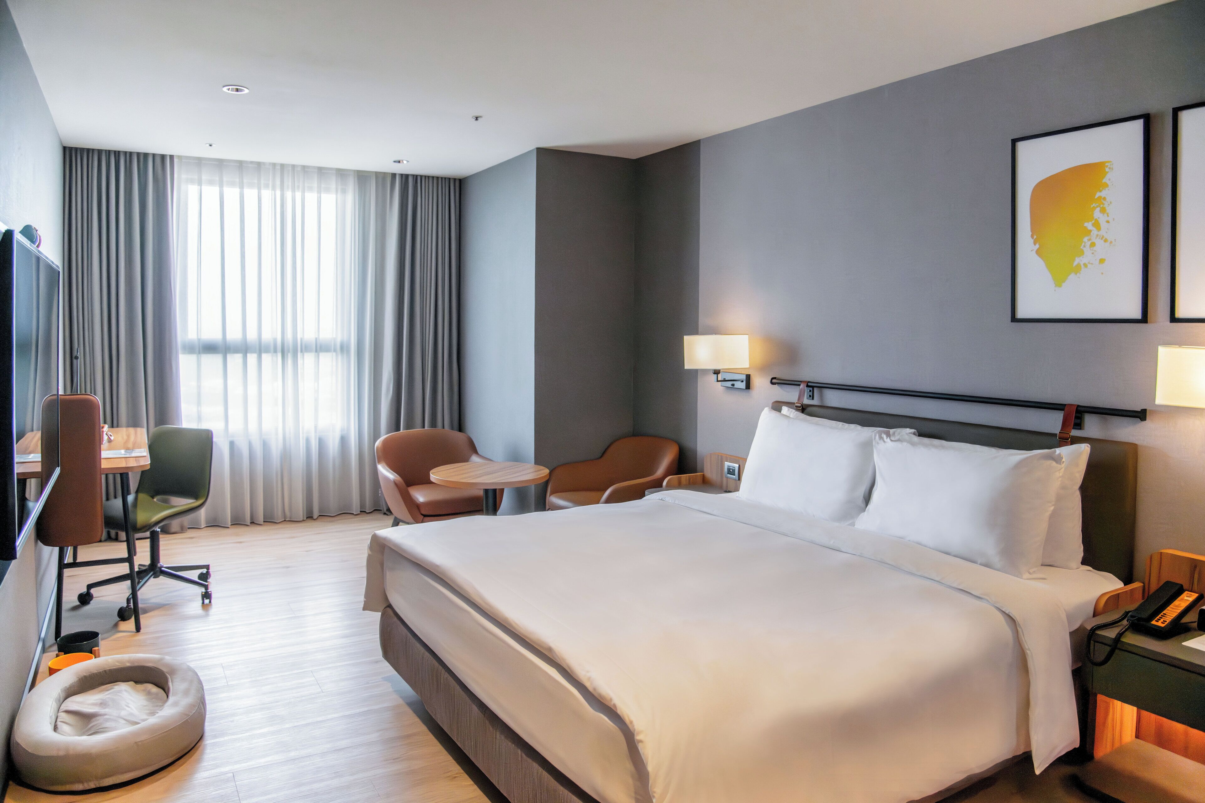 Hotellihuone, jossa on suuri sänky, työpöytä tuolilla, pieni pyöreä pöytä ja sohva.