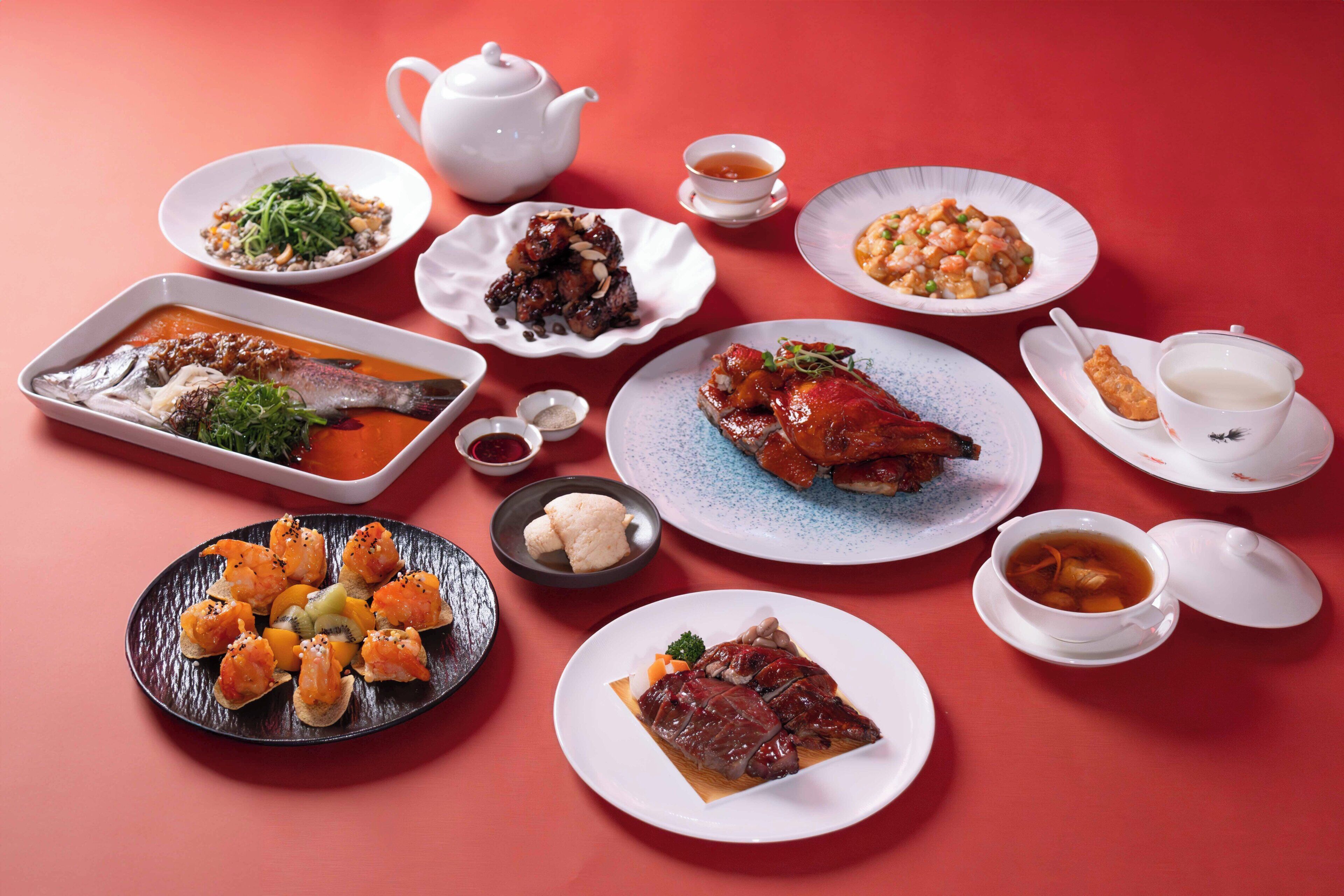 A variety of dishes arranged on a table, including seafood, vegetables, and meat, with a teapot and cups.