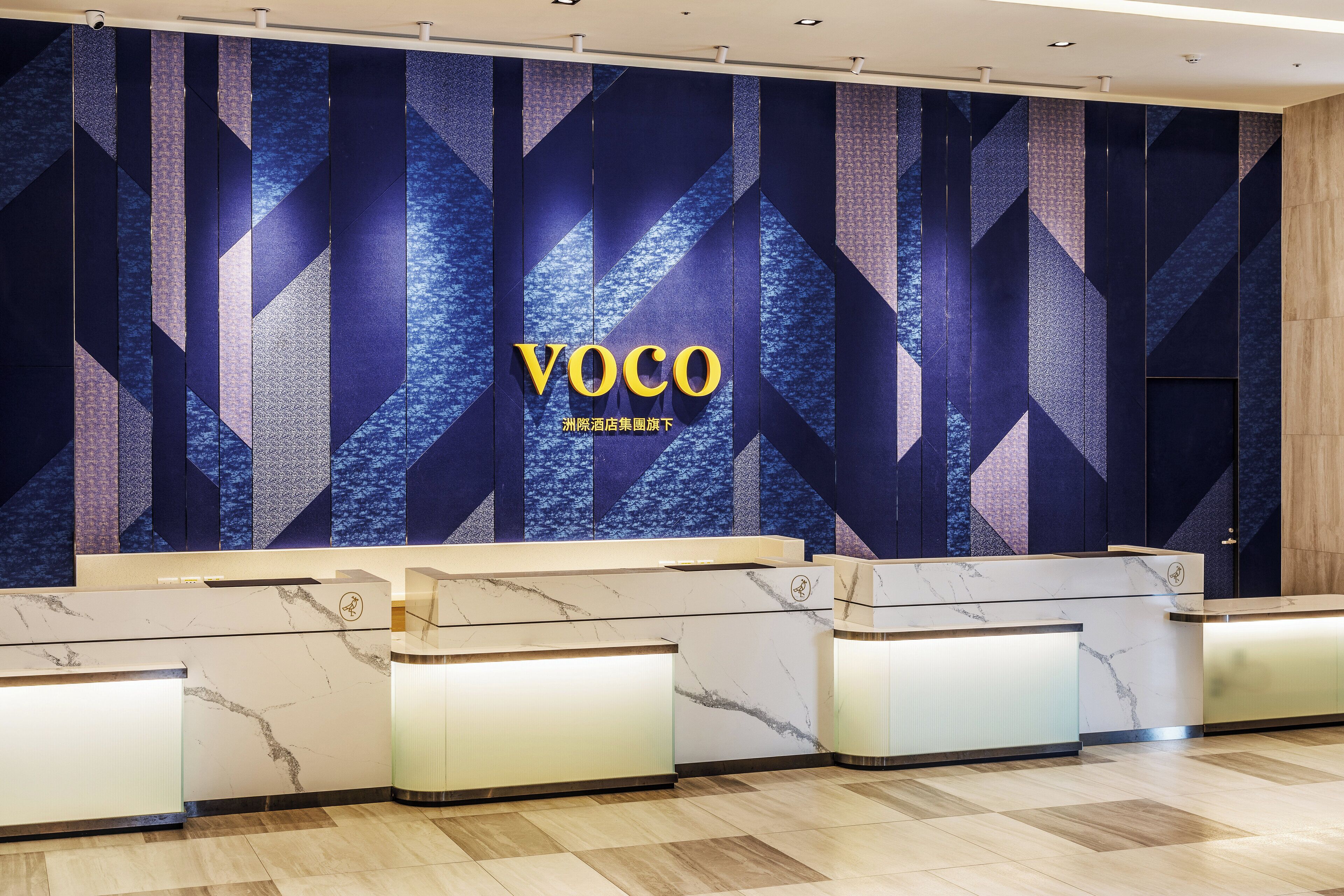 A reception area with a geometric patterned wall and a marble reception desk.