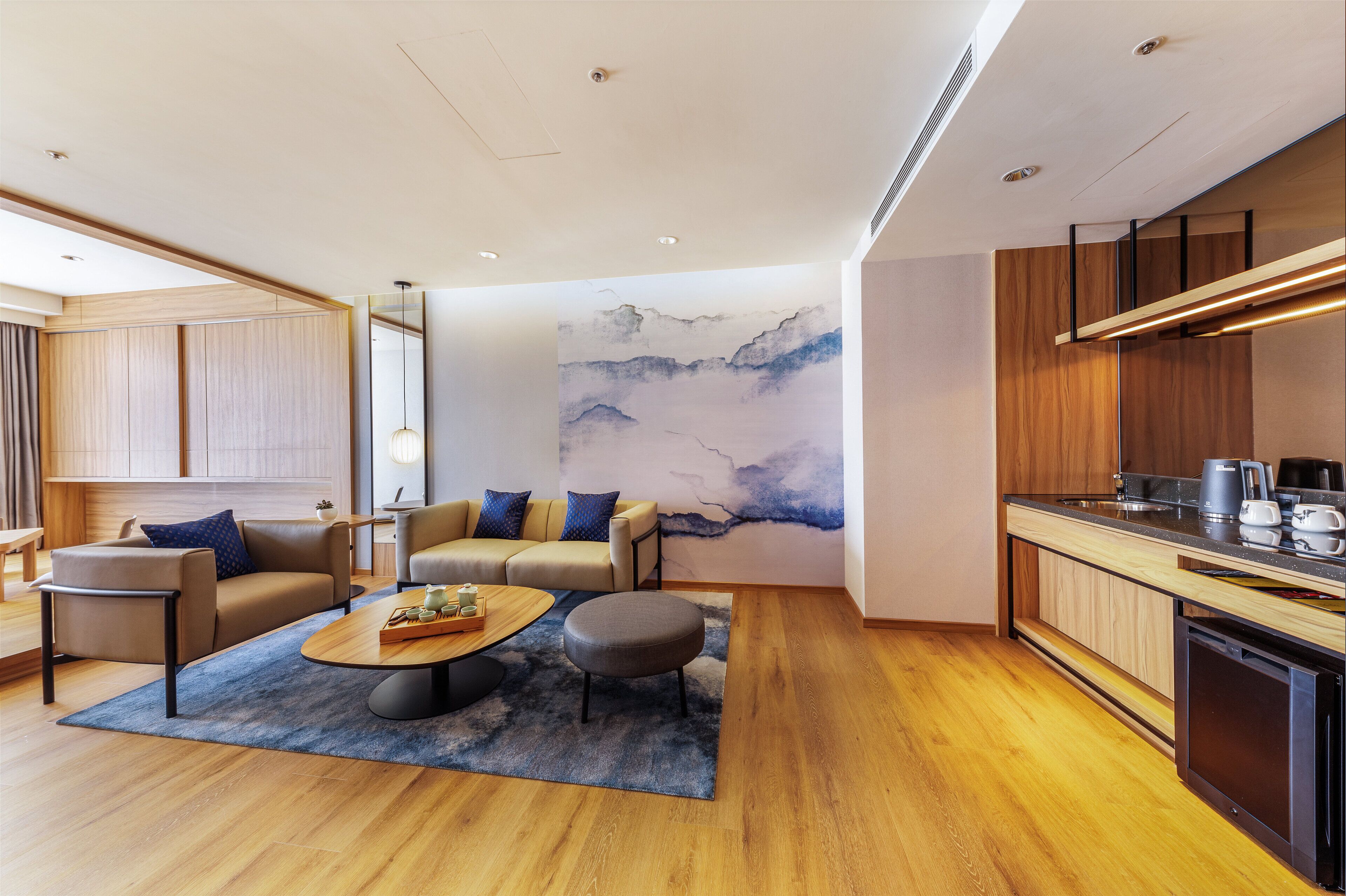 Una sala de estar moderna con sofá, reposapiés, mesa de centro y un gran mural abstracto en la pared.