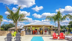 A beachside pool area with Adirondack chairs, a covered seating area, and palm trees. - Holiday Inn Express & Suites Macclenny by IHG (MacClenny)