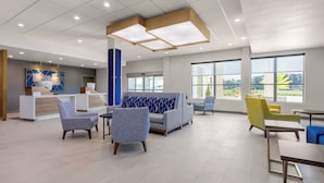 A spacious lobby with a reception desk, seating area, and large windows offering views of the outdoors. - Holiday Inn Express & Suites Macclenny by IHG (MacClenny)