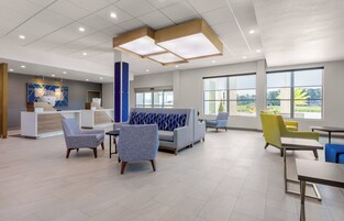 Un vestíbulo amplio con mostrador de recepción, zona de estar y grandes ventanales que ofrecen vistas al exterior.
