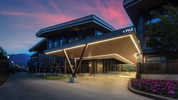 A modern hotel with a covered entrance, a sign reading "Well", and a landscaped garden with flowers. - EVEN Chongli by IHG (Zhangjiakou)