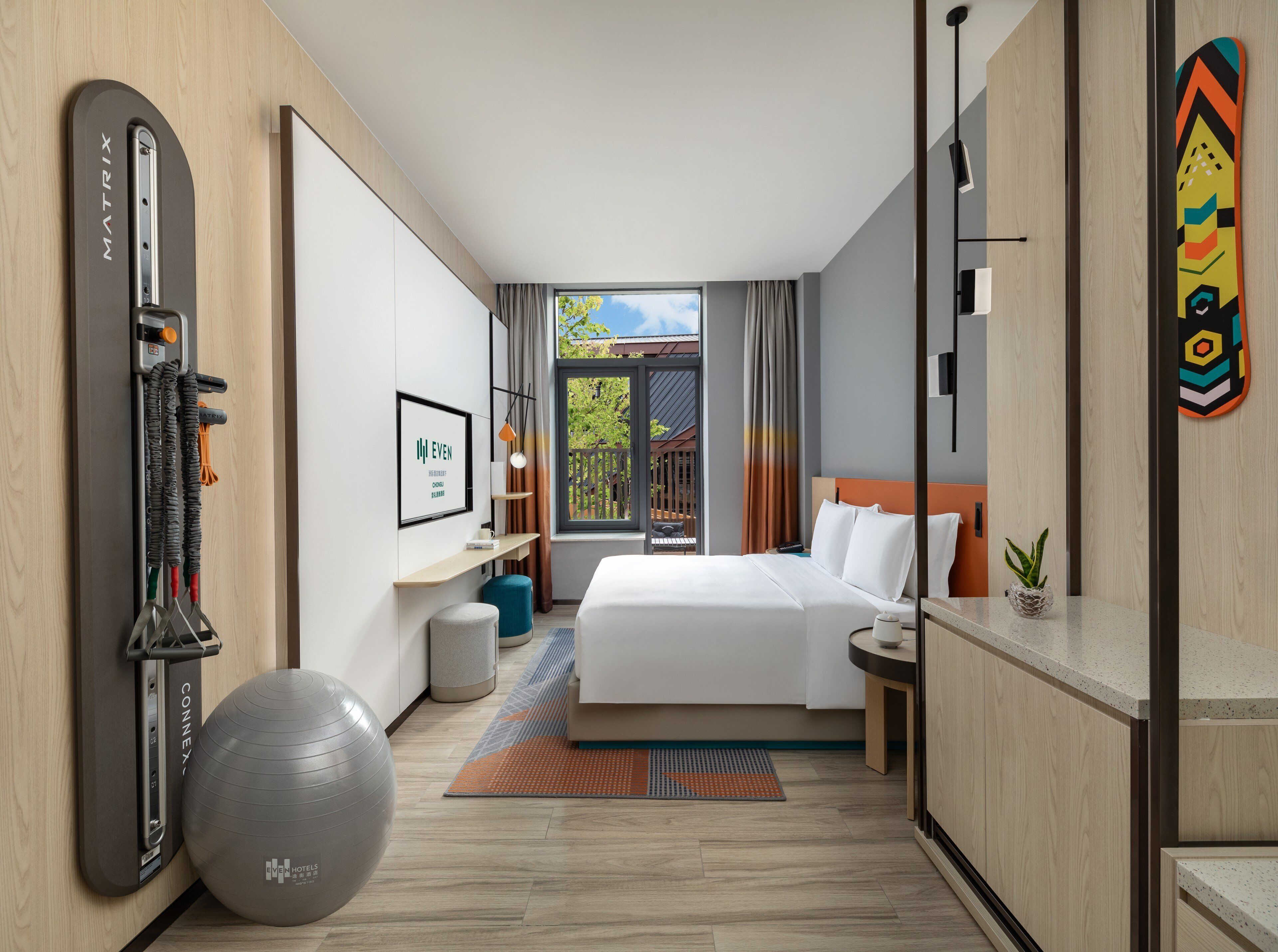 A hotel room with a bed, exercise ball, and a view of the outdoors.