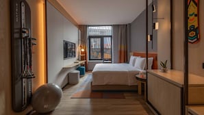 A hotel room with a bed, bedside table, exercise ball, and a large window with curtains. - EVEN Chongli by IHG (Zhangjiakou)