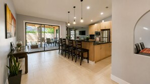 Una cocina moderna con armarios de madera, una zona de comedor con sillas y un gran ventanal.