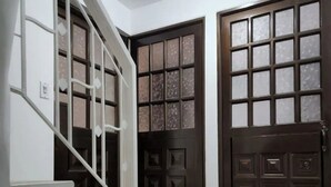 Una escalera conduce a una plataforma con dos puertas de madera oscura, una con paneles de vidrio esmerilado.