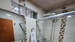 Un baño con ducha envuelta en vidrio, lavamanos e inodoro.